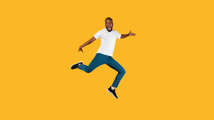 African American Guy Jumping And Shouting Posing Over Yellow Background