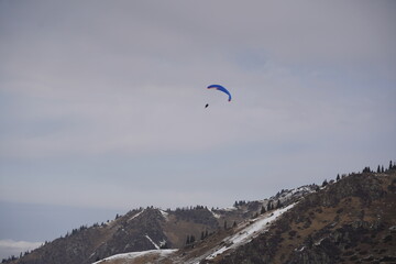 Almaty, Kazakhstan - 03.08.2021 : Tourists fly by parachute over a mountainous area near Almaty