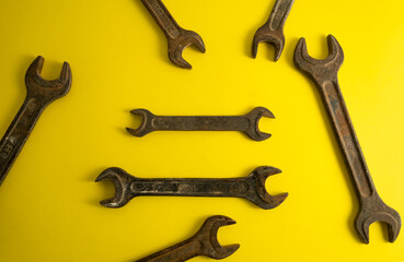 The old rusty  wrench on the yellow background with traces of dirt