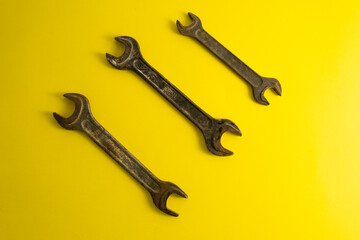 The old rusty  wrench on the yellow background with traces of dirt