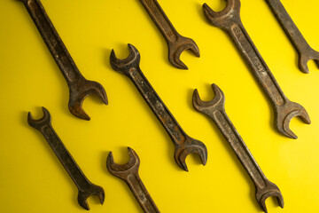 The old rusty  wrench on the yellow background with traces of dirt