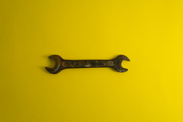 The old rusty  wrench on the yellow background with traces of dirt