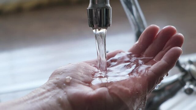 Drinking water from the tap flows into the woman's hand