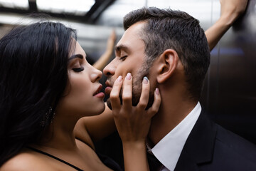 Side view of woman kissing brunette boyfriend in elevator on blurred background © LIGHTFIELD STUDIOS
