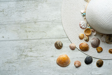summery scene with pamela hat on white wooden background with shells and copyspace
