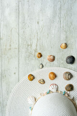 summery scene with pamela hat on white wooden background with shells and copyspace