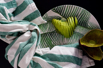 Avocado with heart shape in plate with leaves and striped fabric