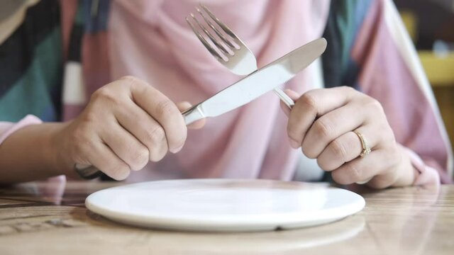 women hand holding cutlery with empty plate waiting for food 