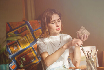 young artist moulding raw clay in art studio. Girl molds from clay sculpture in the artist's...