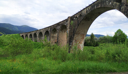 Fototapeta na wymiar Old railway stone bridge or viaduct in mountains