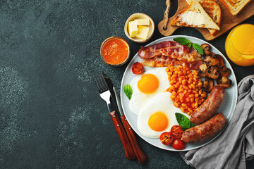 Full English breakfast on a plate with fried eggs, sausages, bacon, beans, toasts and coffee on...