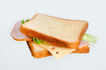A sandwich with cheese and meat hangs in the air on a white background