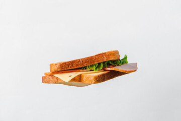 A sandwich with cheese and meat hangs in the air on a white background