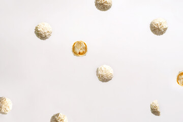 Candies in coconut chips are tossed in the air on a white background. Beautiful background