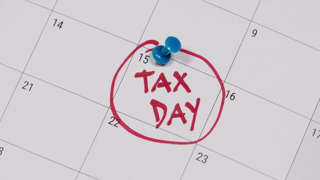 Pinning tax day on April 15 calendar and marked in red. Deadline for 1040 form return.