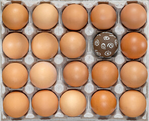 Easter eggs. Celebration Easter. Eggs in carton. Eggs in box. Healthy Farm Food in eco packaging. One colorful easter egg among the raw, unpainted eggs. Holiday easter decoration.