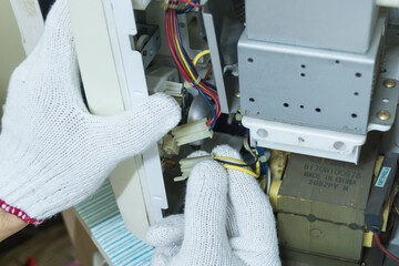 Technician repair microwave oven, Checking microwave magnetron, Home appliances repair service.