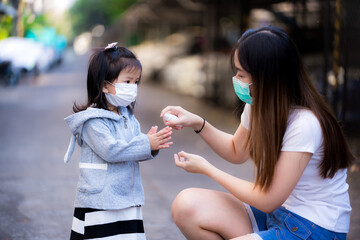 Women spray alcohol to wash hands Asian girl. Family wear medical face mask. Aunt and granddaughter...