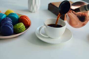 Cup of coffee, multicolored macaroons, turkish coffee pot on white background