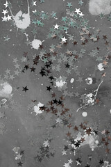 
texture of gray concrete with spots of white paint and silver confetti stars. moon surface