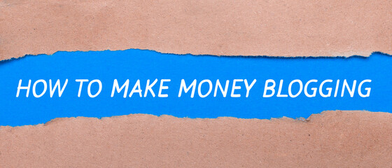 A strip of blue paper with the words HOW TO MAKE MONEY BLOGGING between the brown paper. View from above