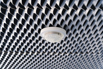 A round light hanging from the ceiling of a gray twisted mesh