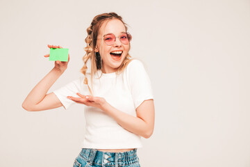 Beautiful woman in sunglasses.Smiling model showing, presenting green credit card for making...
