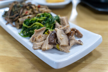 In Korean cuisine, side dishes such as seasoned vegetables are served on a white plate.