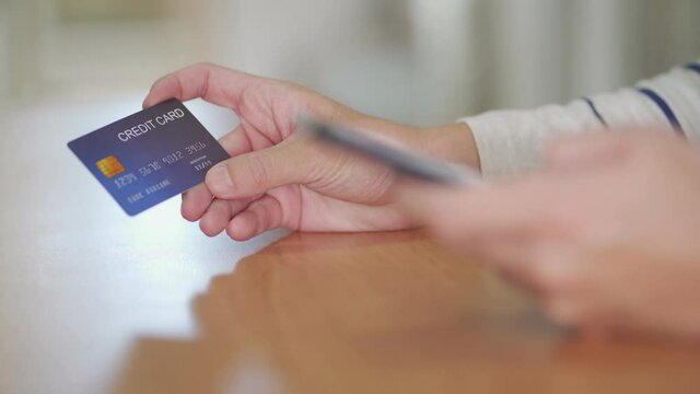 Indoor shot of men hand and smartphone.  While typing credit card mock up number information and CCV security code for online payment transaction. Digital banking with internet communication.