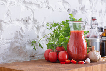 Tomato sauce with red chili in a glass jar on a wooden table. kitchen with white walls