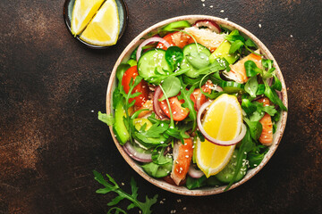 Fresh salad with grilled chicken, cherry tomatoes, arugula, red onion, avocado, sesame seeds and lemon oil dressing. Healthy food concept. Top view. Copy space