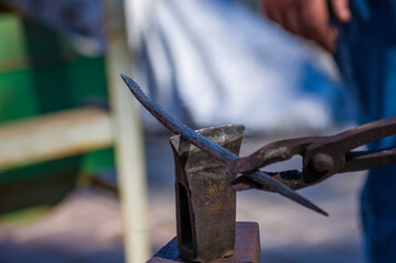 blacksmith performs the forging of hot glowing metal on the anvil