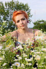 Beautiful young girl with red hair on a flower lawn enjoying nature. Harmony concept.