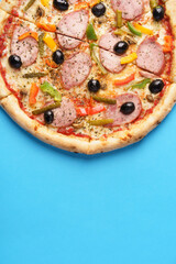 Close-up of Italian Pizza with homemade sausage, Mozzarella, Bulgarian pepper, Olives, Small cucumbers, Champignons, Oregano. Blue background. Copy Space