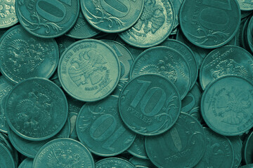 Surface of many Russian coins of 10 ten rubles. Dark green tinted background. Money wallpaper. Backdrop on an economic, financial or banking theme in Russia. View from above. Macro