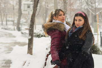 Photoshoot of two sisters having fun in the park on a snowy winters day.