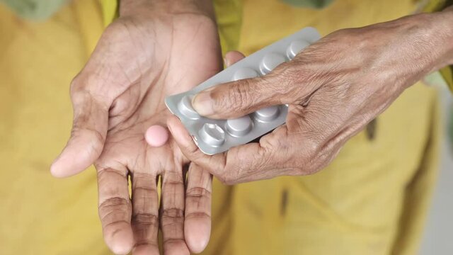 top view of senior women taking medical pill from a bister pack 