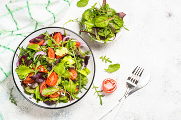 Green salad from fresh salad leaves and vegetables at white kitchen table. Healthy vegan food. Top view image.
