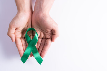 World kidney day, hands holding green ribbon awareness of kidney disease isolated white background.