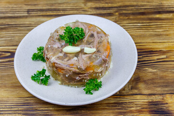 Meat aspic in a plate on a wooden table. Traditional russian dish