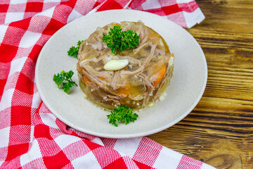 Meat aspic in a plate on a wooden table. Traditional russian dish