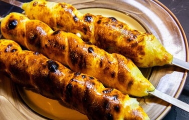 Traditional Georgian dish khachapuri, skewers of roasted cheese on a skewer into the dough on a wooden table.