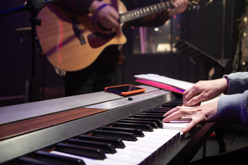 Musicians play musical keys and acoustic guitar in a music studio.