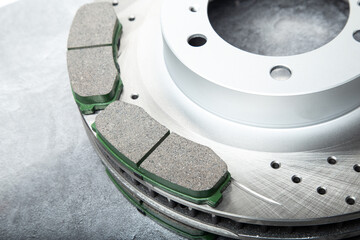 brake pads and perforated brake discs on a stone gray table