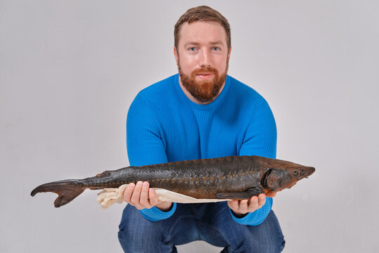 man with a smoked sturgeon in his hands. on a white background of a cyclorama, studio photo