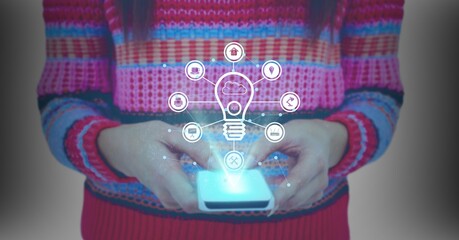 Digital interface with digital icons over mid section of woman using smartphone