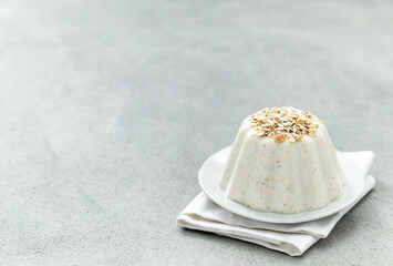 Creamy oatmeal pudding on a plate on a linen napkin on a light gray background copy space