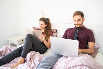 Caucasian couple lying in bed and working from home. Palma de Mallorca, Spain