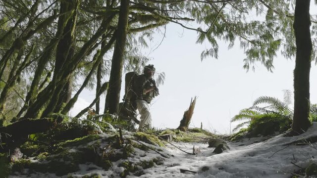 Army Man wearing Tactical Uniform and holding Machine gun in the Outdoor Rain Forest. Winter Warfare. Taken in British Columbia, Canada. Slow Motion