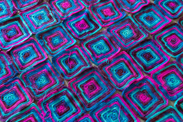 Crochet product from multicolored threads. Many squares crocheted. Handmade backdrop. Flat lay